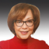 Christine Stepp wearing a red shirt and glasses looks at the camera